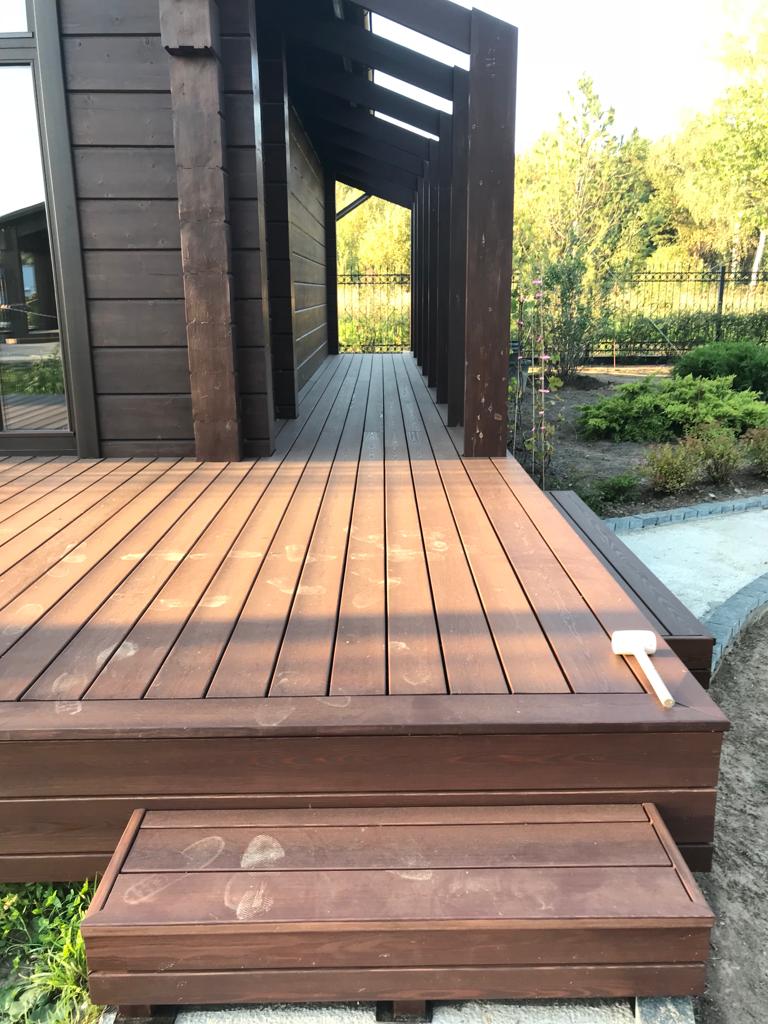 Dark-stained wood deck with covered walkway and steps